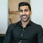 Smiling businessman holding documents at his desk, embracing productivity in a modern office.
